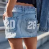 Fustă-pantalon mini din denim cu talie joasă, modelul „Class of ’26” Fustă-pantalon mini din denim cu talie joasă, modelul „Class of ’26”
