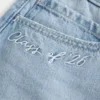 Fustă-pantalon mini din denim cu talie joasă, modelul „Class of ’26” Fustă-pantalon mini din denim cu talie joasă, modelul „Class of ’26”