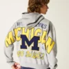 Hanorac cu glugă și fermoar, model boxy, cu imprimeu grafic Wolverines, Universitatea din Michigan Hanorac cu glugă și fermoar, model boxy, cu imprimeu grafic Wolverines, Universitatea din Michigan