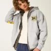 Hanorac cu glugă și fermoar, model boxy, cu imprimeu grafic Wolverines, Universitatea din Michigan Hanorac cu glugă și fermoar, model boxy, cu imprimeu grafic Wolverines, Universitatea din Michigan
