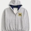 Hanorac cu glugă și fermoar, model boxy, cu imprimeu grafic Wolverines, Universitatea din Michigan Hanorac cu glugă și fermoar, model boxy, cu imprimeu grafic Wolverines, Universitatea din Michigan
